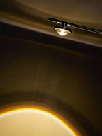 Close view of the small lamp head on this Clérachic floor lamp, with the warm edge of its light beam below.