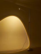 This Clérachic floor lamp fills a golden wall with a warm arched glow, its cord trailing to a square chrome base.