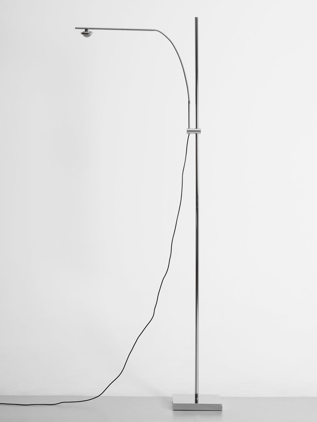 Full-height view of this Clérachic chrome floor lamp with its cord looping down to a square base on a pale background.