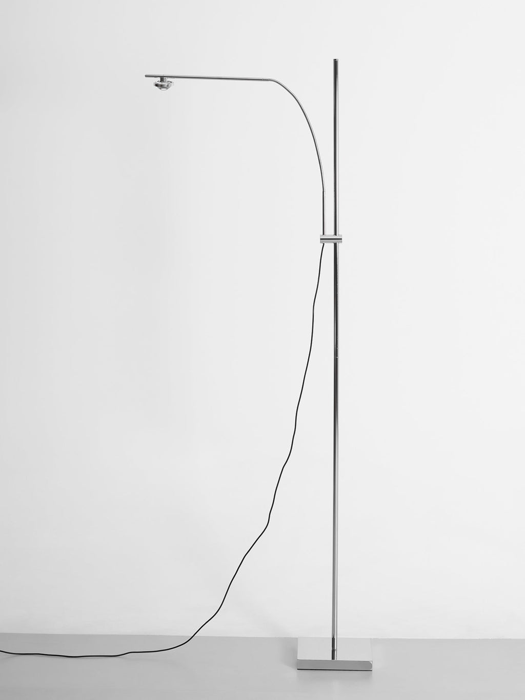A Clérachic chrome floor lamp with a long, gently curved arm and a square base, on a soft white background.