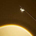 Close view of the glass lens in the lamp head of this Clérachic floor lamp, with a warm arc of light below.