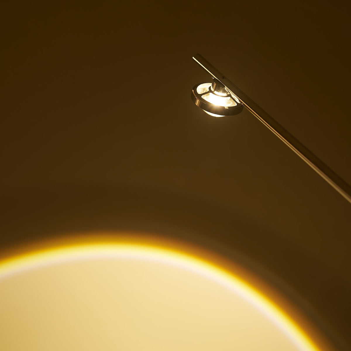 Close view of the glass lens in the lamp head of this Clérachic floor lamp, with a warm arc of light below.