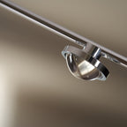 Close view of the round glass lens and chrome ring on the lamp head of this Clérachic floor lamp.