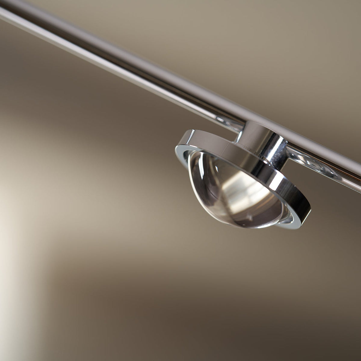 Close view of the round glass lens and chrome ring on the lamp head of this Clérachic floor lamp.
