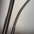Close view of the flexible, ribbed chrome neck where the arm of this Clérachic floor lamp meets the pole.