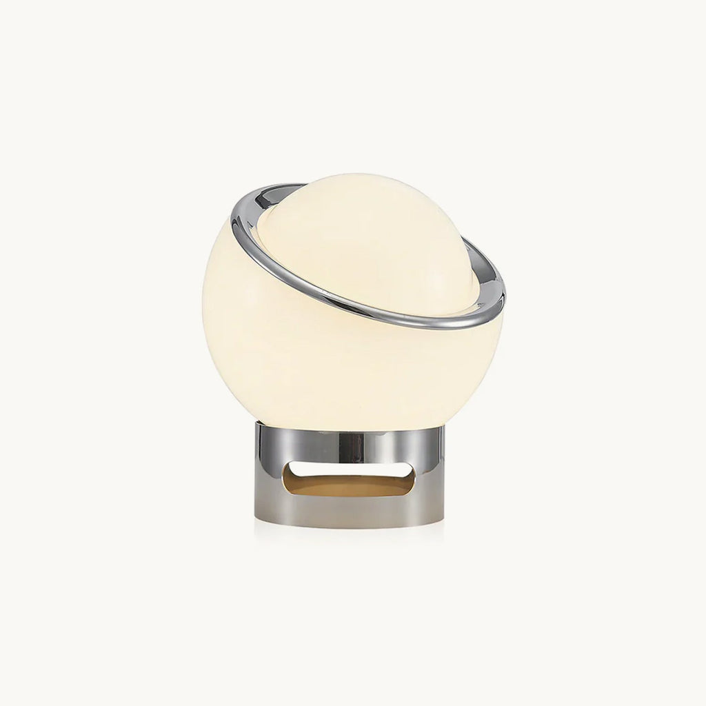 Glowing white glass globe with a tilted chrome ring on a short chrome base, shown on a plain white backdrop as this Clérachic table lamp.