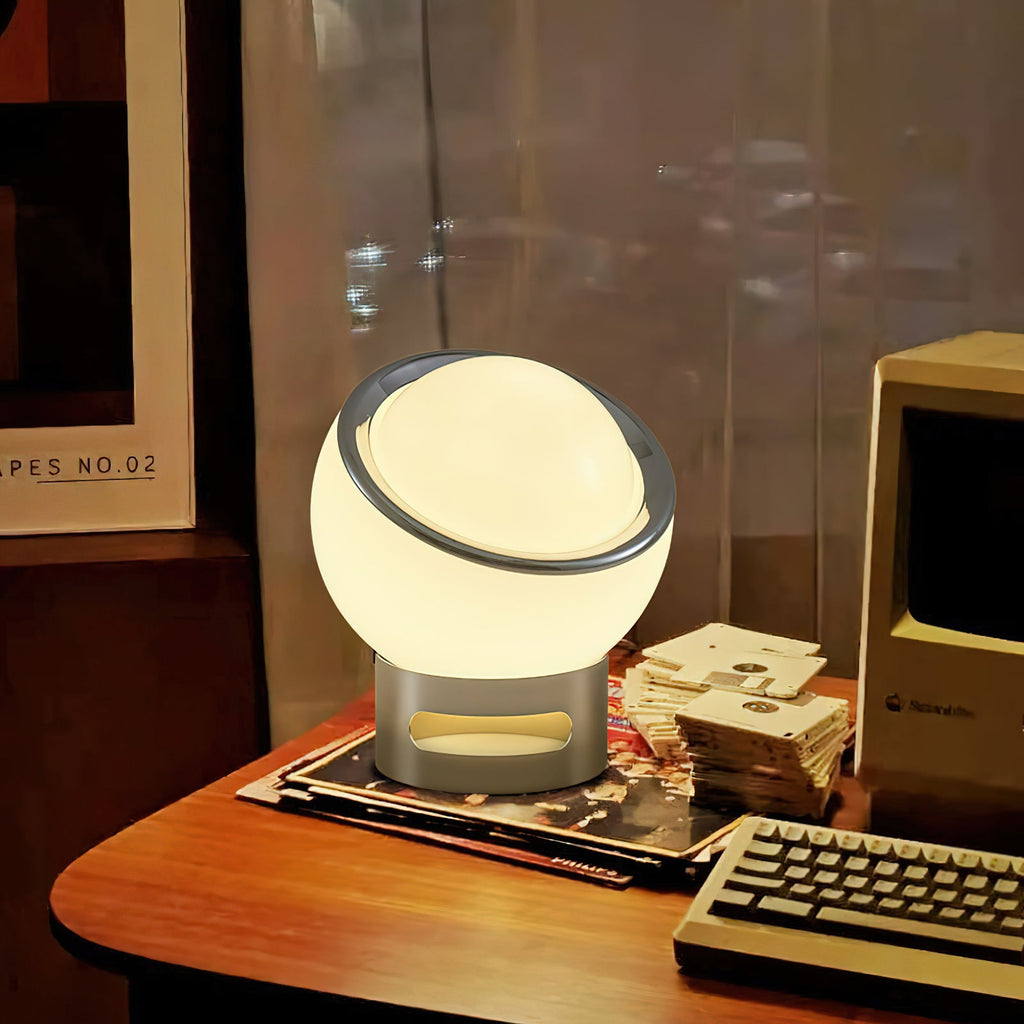 Lit Clérachic table lamp with a white glass globe and chrome base on a wooden desk beside a keyboard and a retro computer.