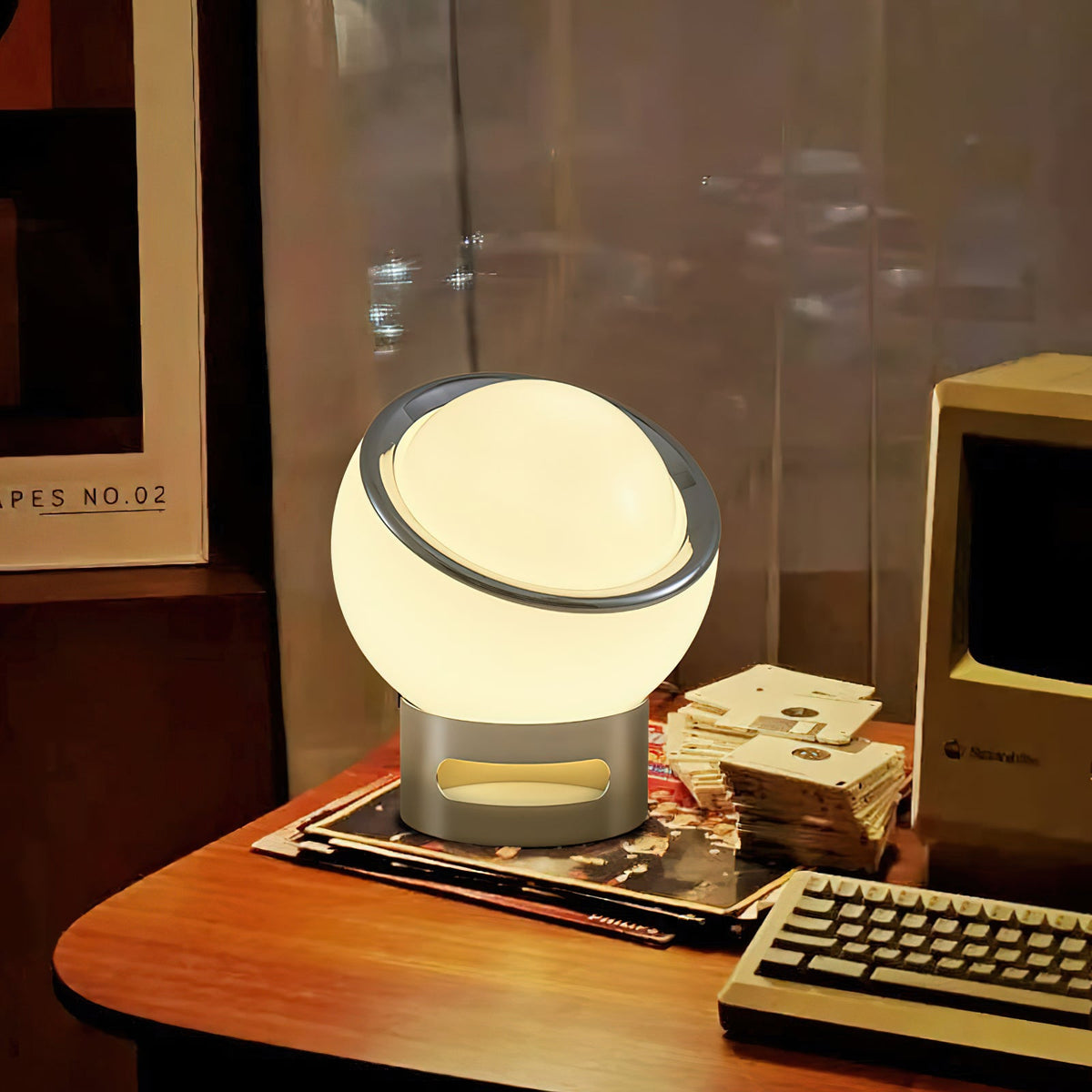 Lit Clérachic table lamp with a white glass globe and chrome base on a wooden desk beside a keyboard and a retro computer.