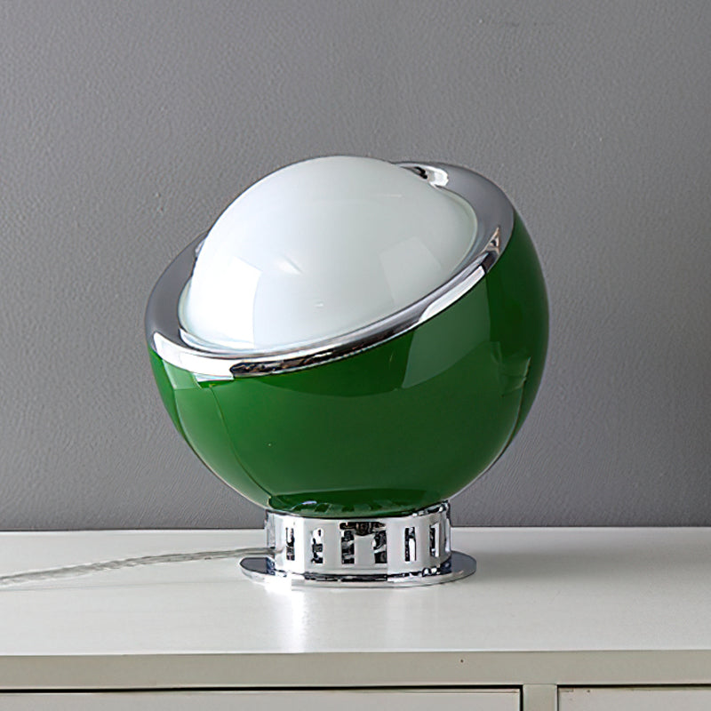 Green Clérachic table lamp with a white dome, chrome ring and ribbed chrome base, on a white cabinet against a grey wall.