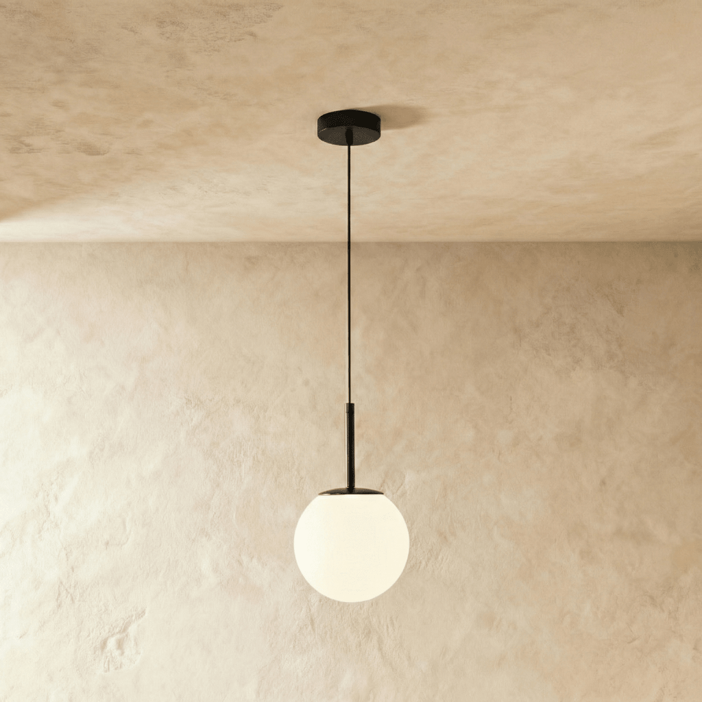 Clérachic Cells pendant light in Straight, Black, a matte black rod holding a frosted glass globe from a plaster ceiling.