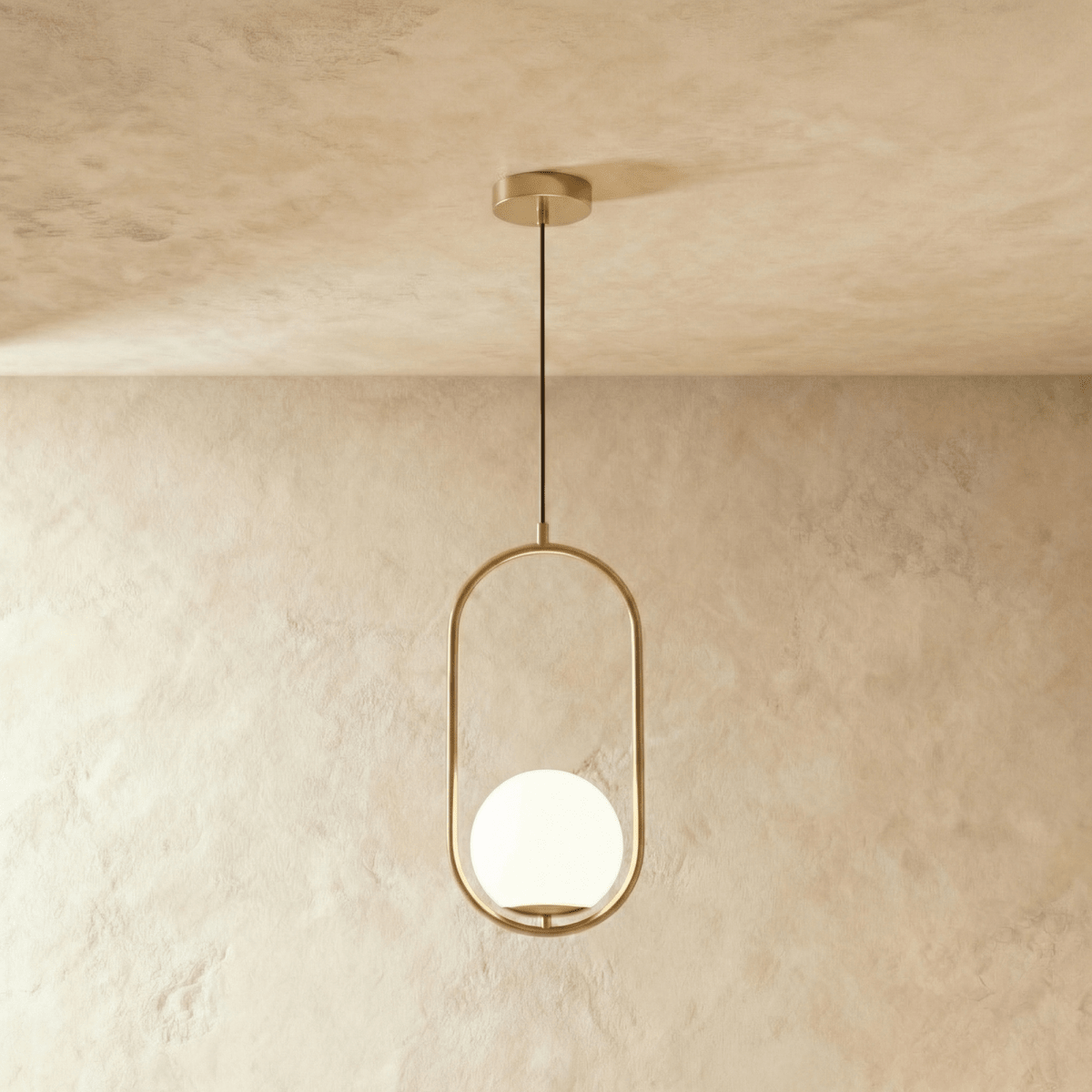 Clérachic Cells pendant light in Oval, Brass, a slim brass frame cradling a frosted glass globe from a black cord.