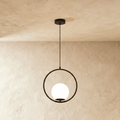 Clérachic Cells pendant light in Circle, Black, a matte black ring cradling a frosted glass globe against plaster.