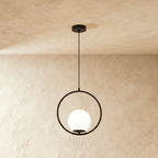 Clérachic Cells pendant light in Circle, Black, a matte black ring cradling a frosted glass globe against plaster.