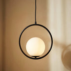 Close-up of the Clérachic Cells pendant light in Circle, Black, its frosted globe glowing warm inside the matte ring.