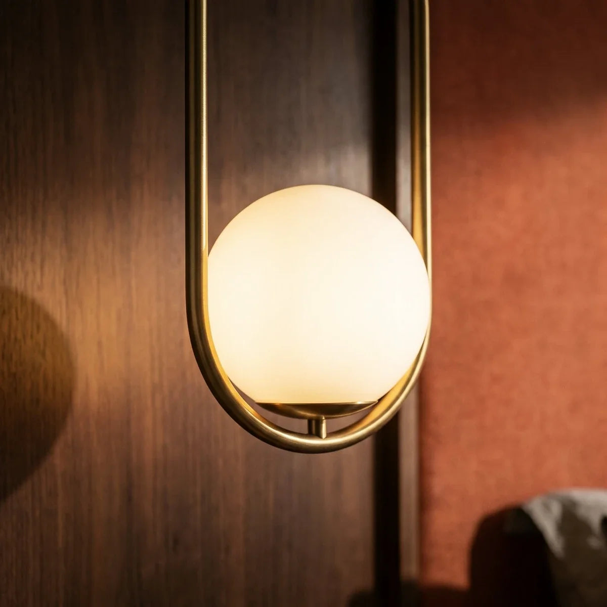 Macro detail of the Clérachic Cells pendant light in Oval, Brass, showing the frosted globe glowing inside its frame.