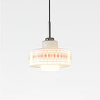 Clérachic pendant with a white opal glass shade, orange lattice print and a chrome cap, lit softly on a plain light backdrop.