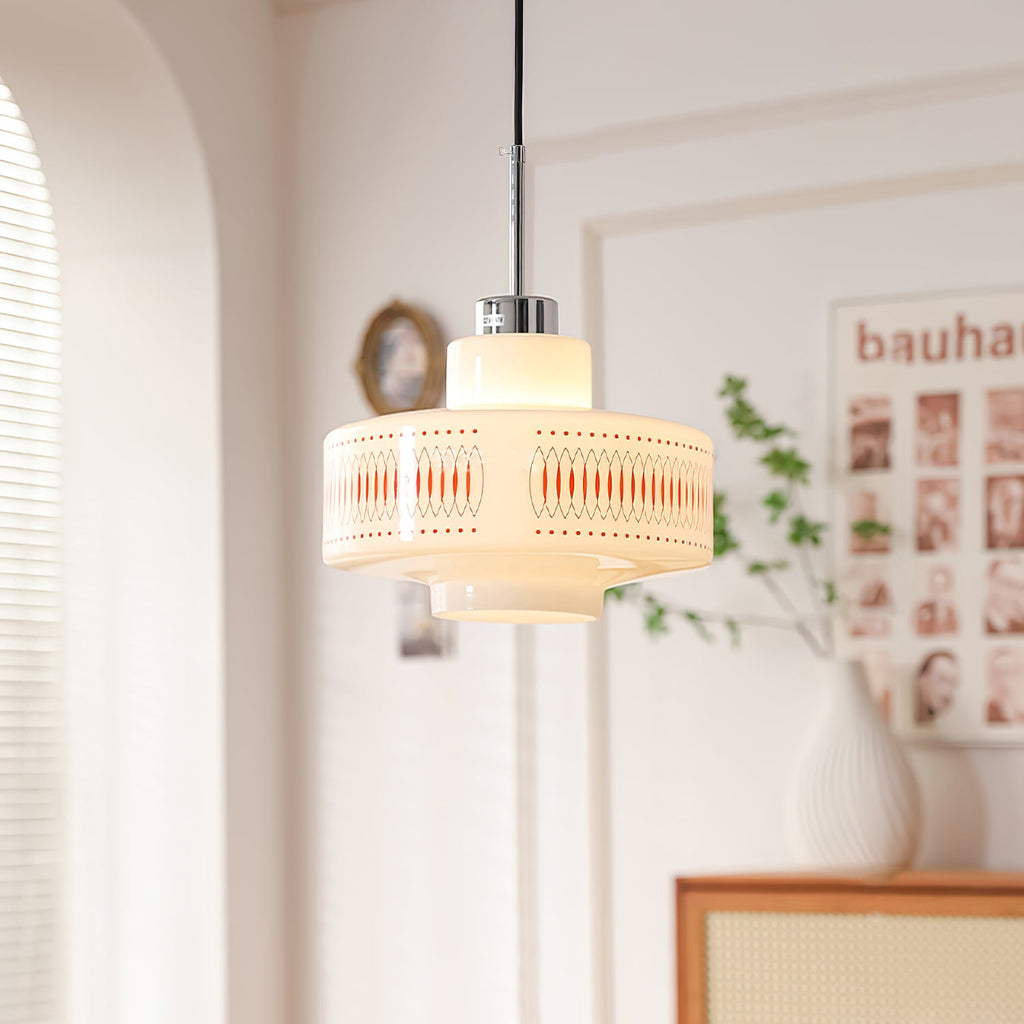 A Clérachic opal glass pendant with an orange lattice band glows beside a white vase, a rattan cabinet and an arched wall.