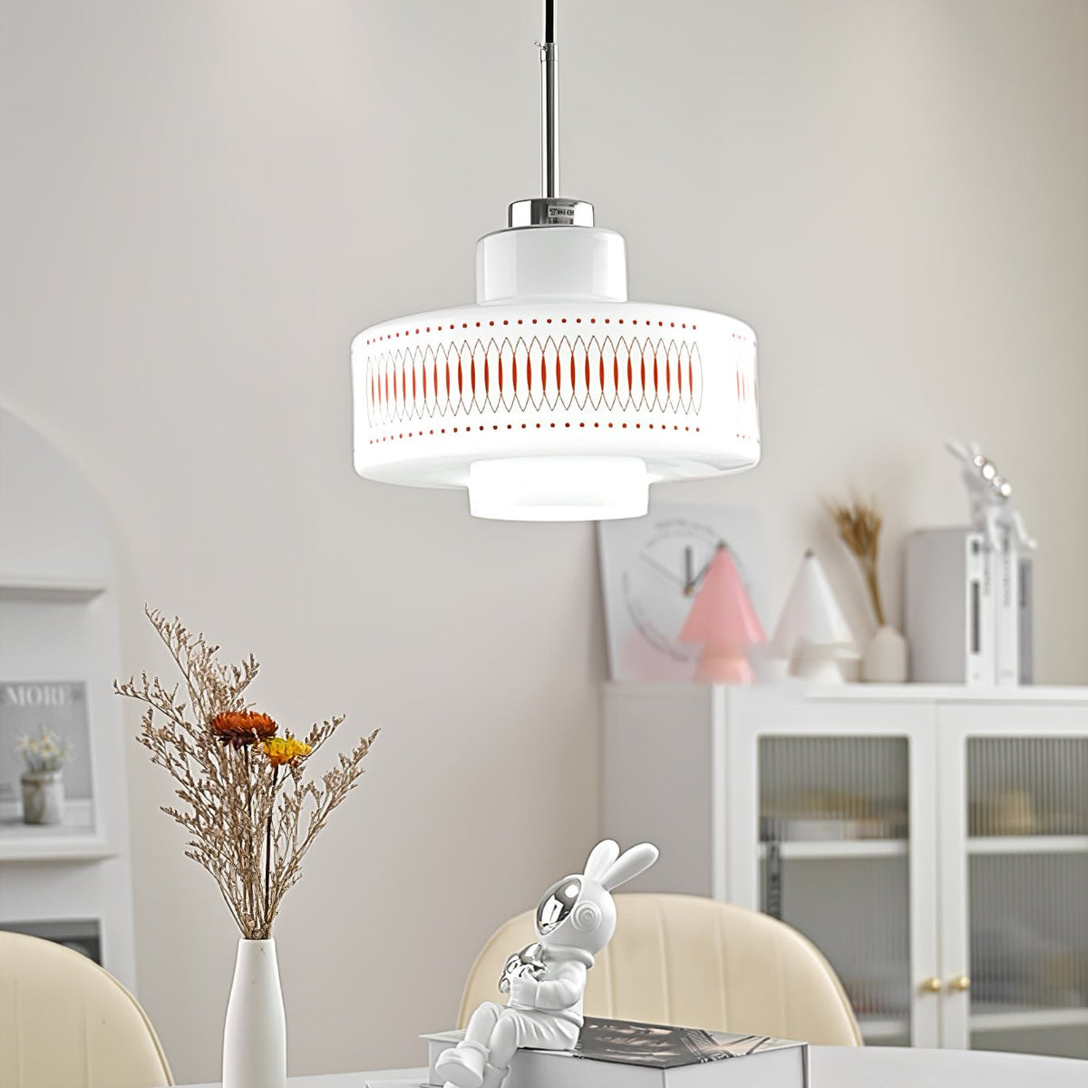 A Clérachic pendant with a printed opal glass shade hangs above a table with dried flowers, a glass cabinet and a rabbit figure.