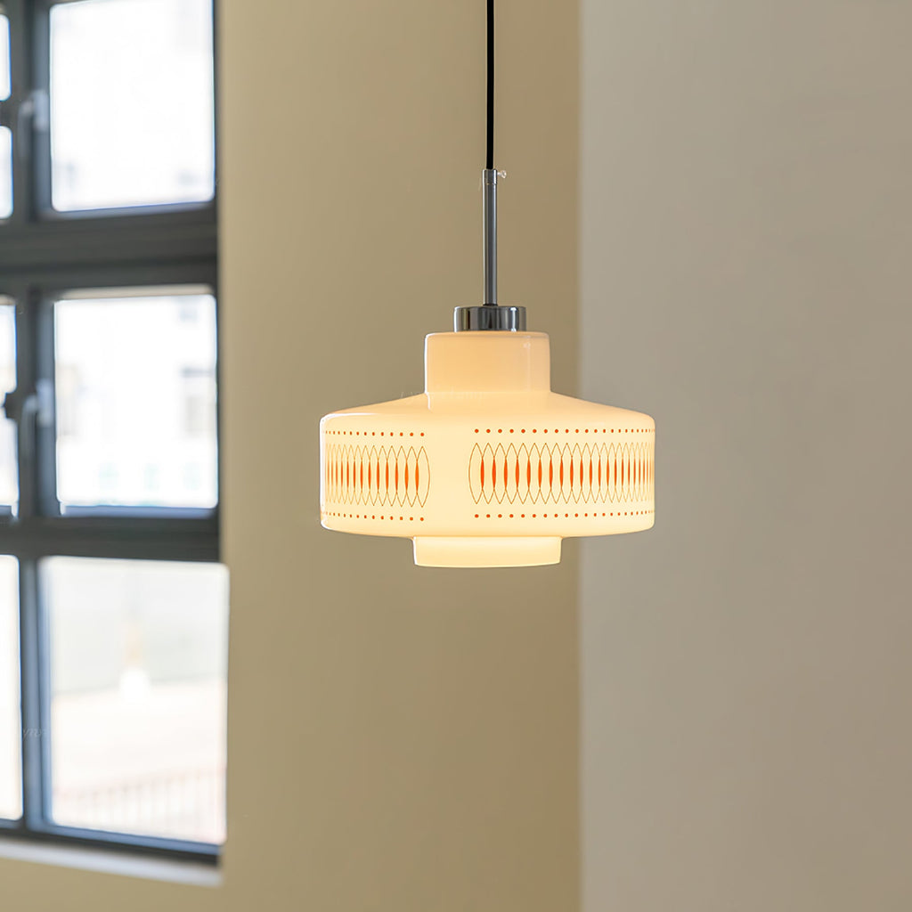 Clérachic pendant with a stepped opal glass shade glows against a cream wall beside a black-framed window.