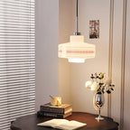 A Clérachic opal glass pendant with an orange lattice band lights a corner with a round dark table, books and white blooms.