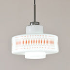 Close view of the stepped opal glass shade and orange printed band on this Clérachic pendant, with a chrome cap above.