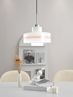 A Clérachic pendant with a white glass drum and orange print hangs above a white table with a vase and a rabbit figure.