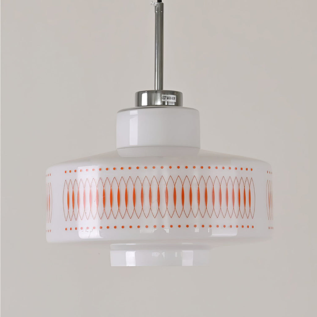 Close view of this Clérachic pendant's white glass shade, orange lattice print and chrome stem against a grey wall.