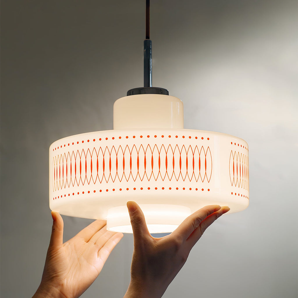 Two hands hold up the underside of this Clérachic pendant, showing the size of its white glass shade and printed band.