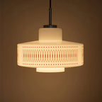 A Clérachic pendant with a stepped opal glass shade glows amber against a deep brown backdrop.