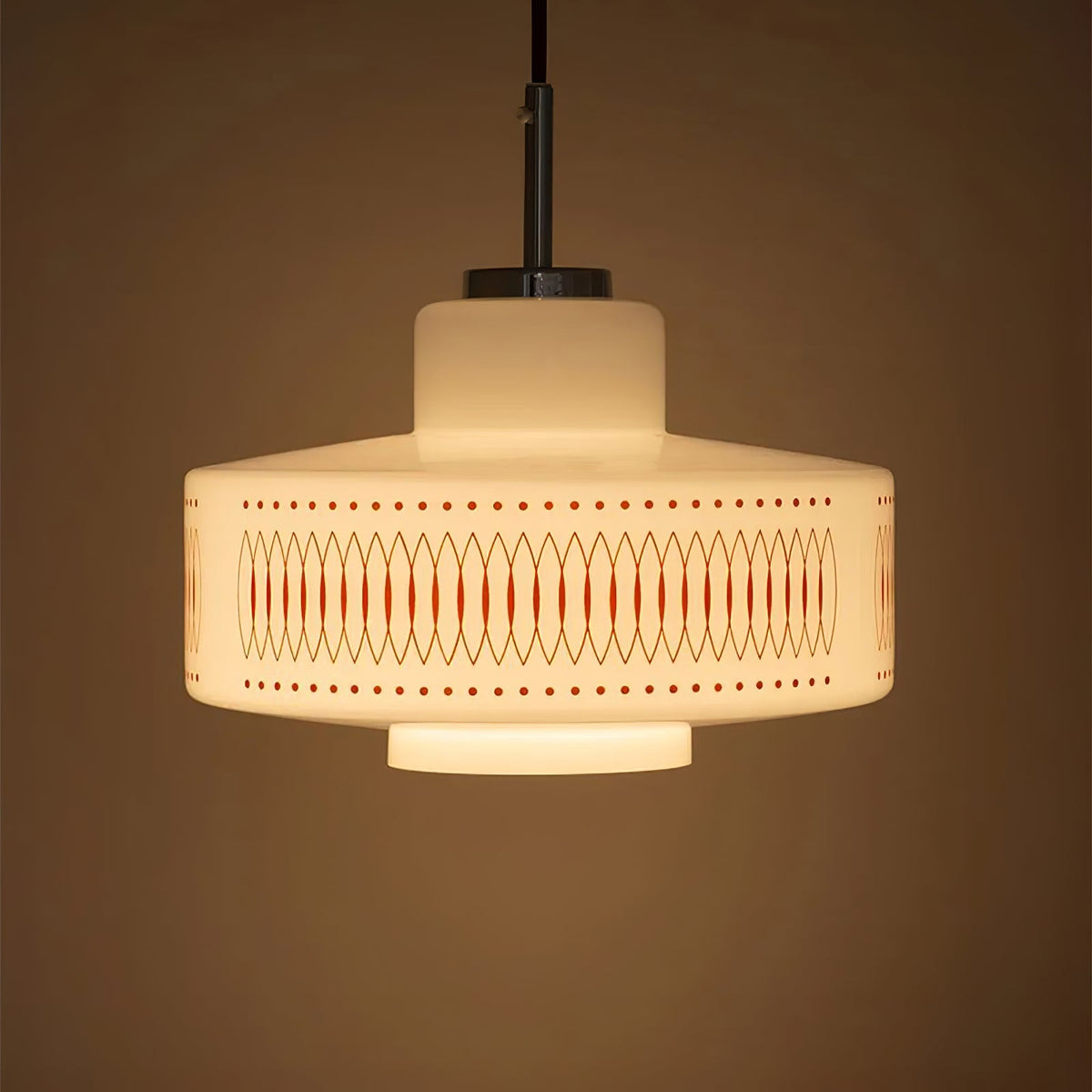 A Clérachic pendant with a stepped opal glass shade glows amber against a deep brown backdrop.