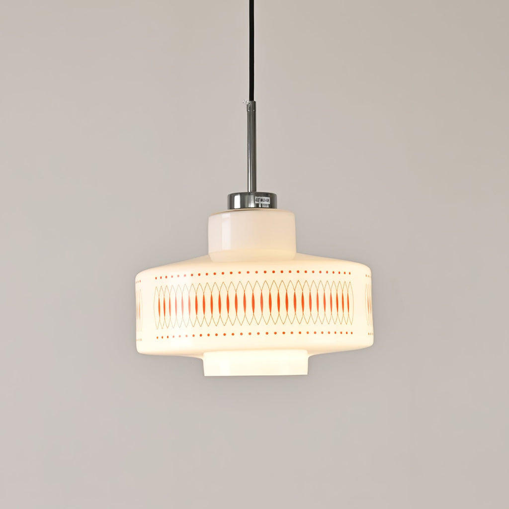 Clérachic pendant with an orange lattice band on a glowing opal shade, hung against a pale grey wall.