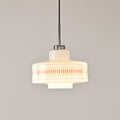 Clérachic pendant with an orange lattice band on a glowing opal shade, hung against a pale grey wall.