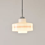 Clérachic pendant with an orange lattice band on a glowing opal shade, hung against a pale grey wall.