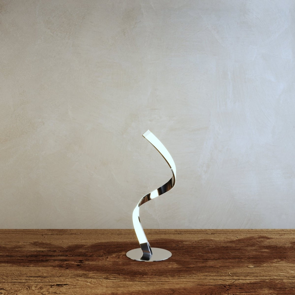 Clérachic spiral LED table lamp with a lit ribbon curve and polished chrome round base, set on a rustic wooden tabletop.