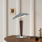 Chrome dome table lamp from Clérachic on a walnut side table, with a small framed print and a steel coffee pot behind it.