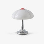 This Clérachic table lamp on a plain white backdrop, a white lobed glass shade with a red cap on a slim chrome stem and round base.