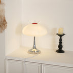 On a white sideboard, this Clérachic lamp glows softly beside a black candlestick, with its white cord trailing down.