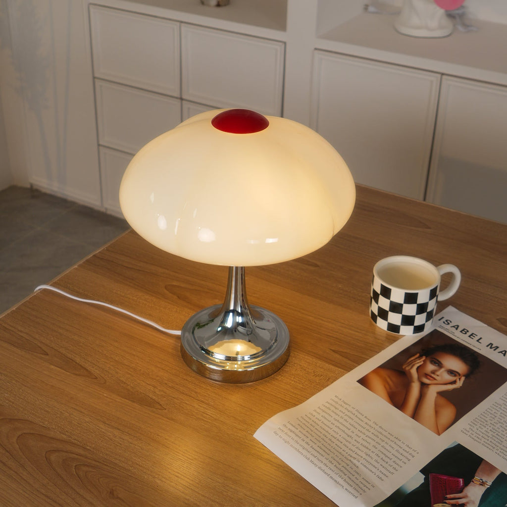 This Clérachic table lamp glowing on a pale wood desk, with a checked mug and a magazine open at the lower right.