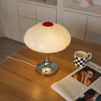 This Clérachic table lamp glowing on a pale wood desk, with a checked mug and a magazine open at the lower right.