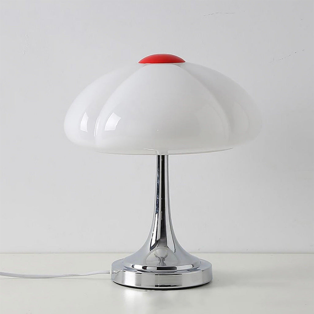Unlit white scalloped shade with a red cap on this Clérachic lamp, standing on a pale surface against a grey wall.