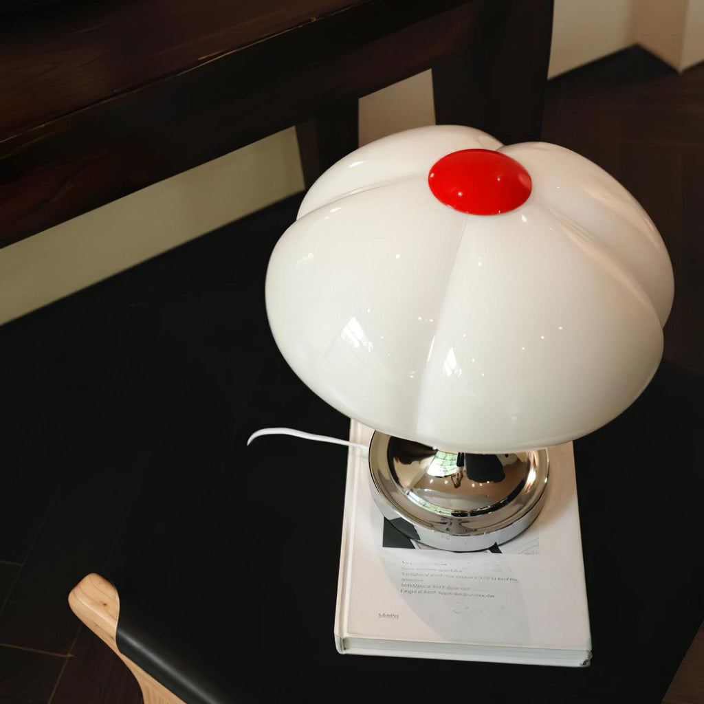 Unlit Clérachic lamp on a hardback book against a dark floor, seen from above with its red cap at the top.