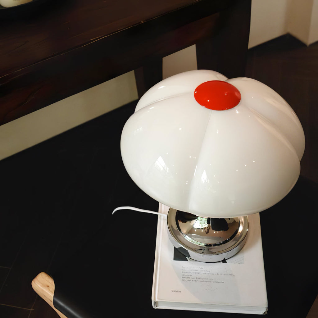 Close view from above of this Clérachic lamp, the white lobed shade and red cap on a book against a dark floor.