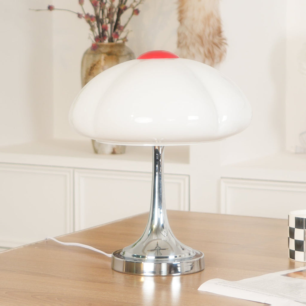 Close view of the white scalloped shade on this Clérachic lamp, unlit, above a chrome stem on a wooden desk.