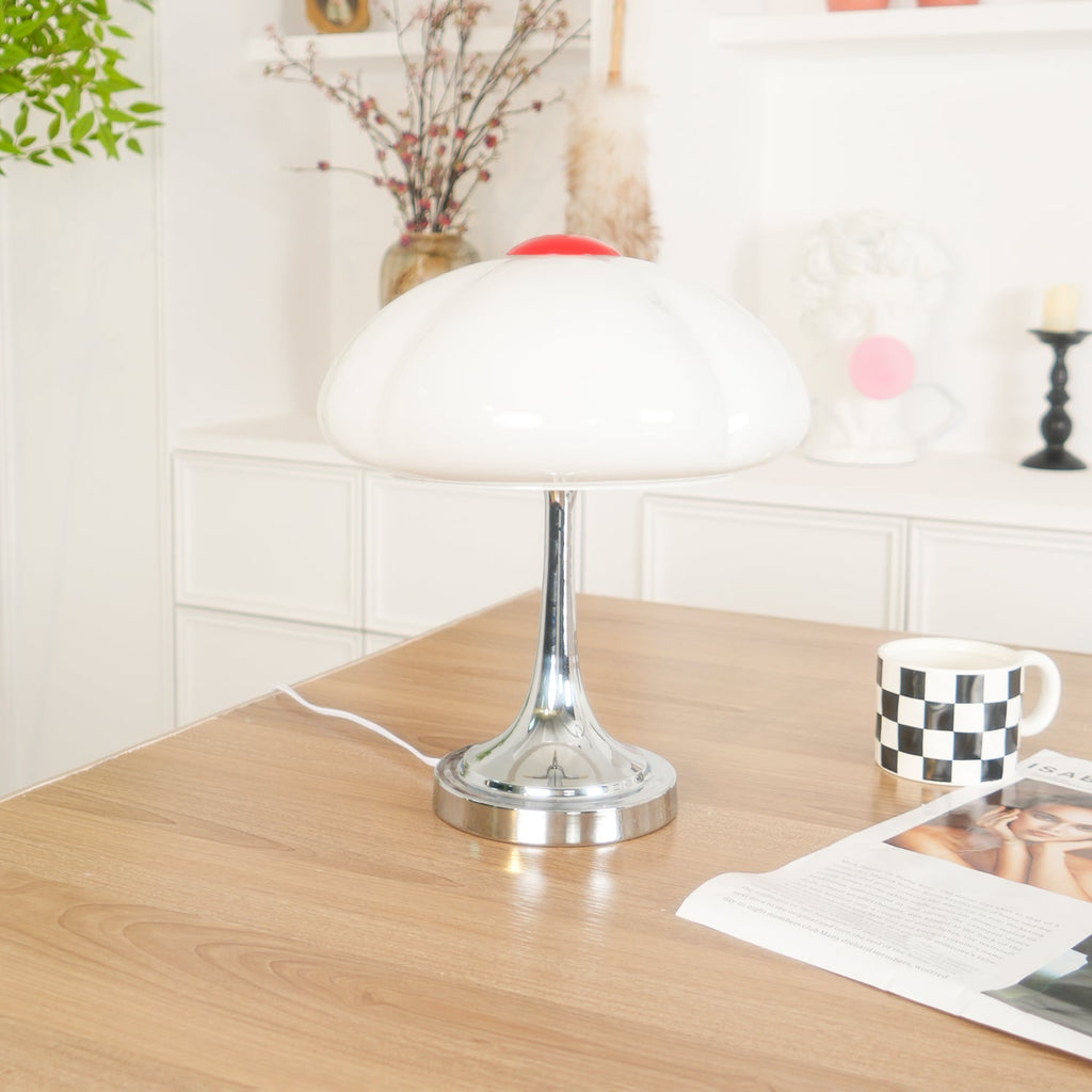 This Clérachic table lamp unlit on a wooden desk, a checked mug and magazine beside it and a plant in the background.