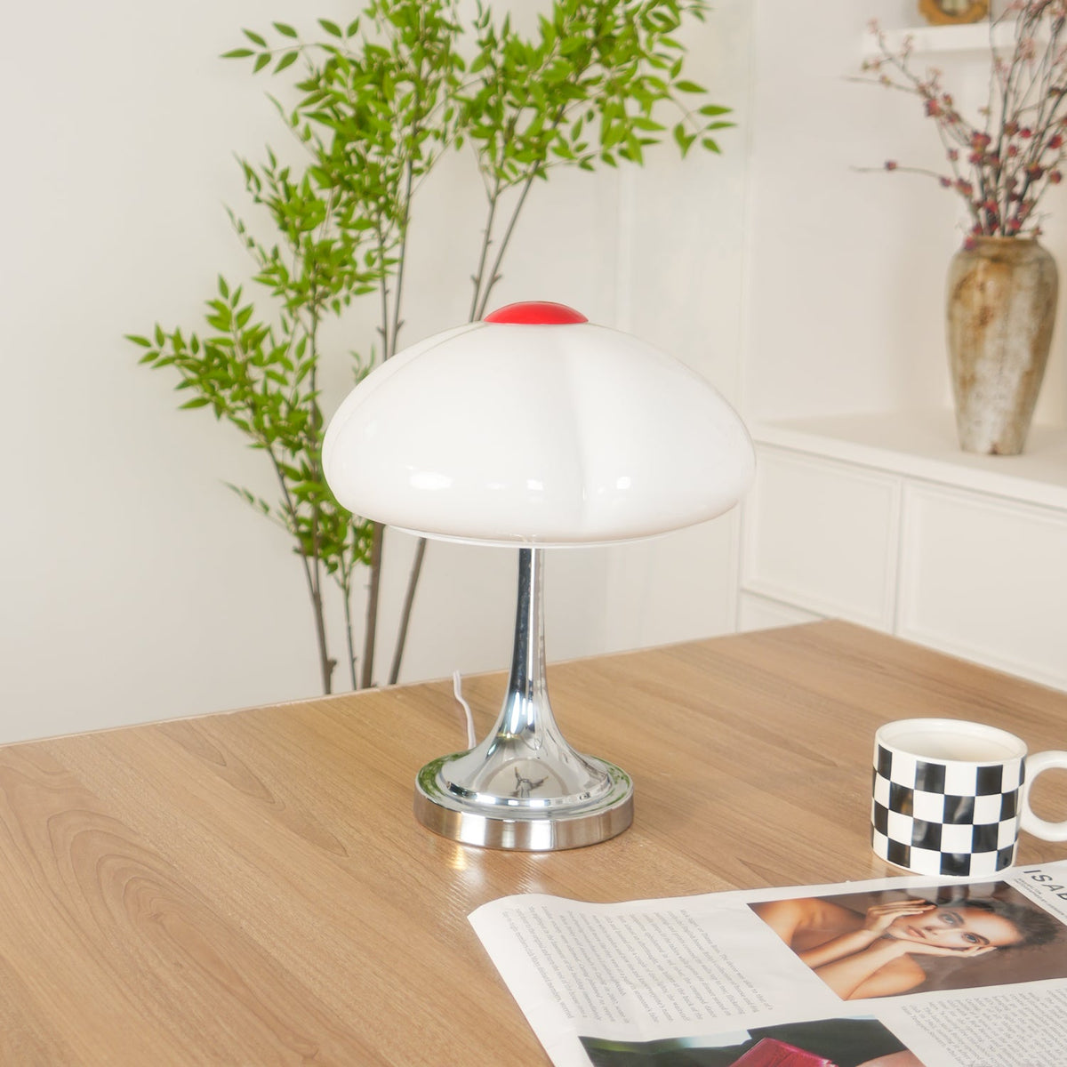 Unlit Clérachic table lamp on a wooden desk, a leafy plant and checked mug behind, and a magazine in the foreground.