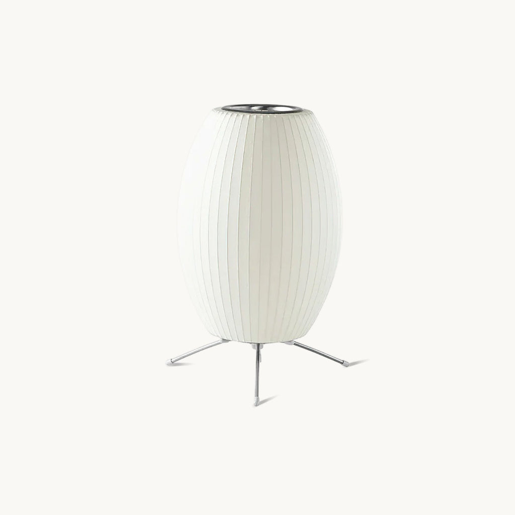 A white oval ribbed shade on a three-legged metal stand, this Clérachic table lamp seen on a plain pale background.