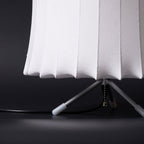 Close view of the lower edge of the white ribbed shade and the tripod legs with white tips on this Clérachic table lamp.