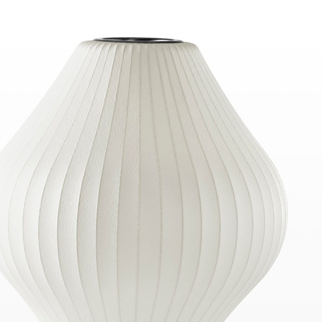 Close view of the white ribbed, pear-shaped shade of this Clérachic table lamp, its fabric-like texture visible.