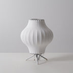 Unlit pear-shaped white Clérachic table lamp on a grey backdrop, its ribbed shade narrowing towards the tripod base.