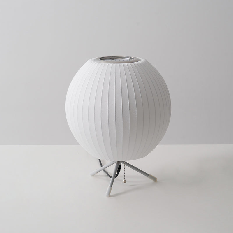 An unlit round Clérachic table lamp on a grey set, its ribbed white shade sitting just above three slim legs.